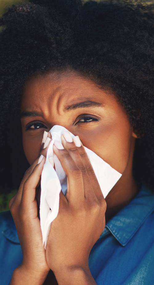 Woman sneezes into tissue