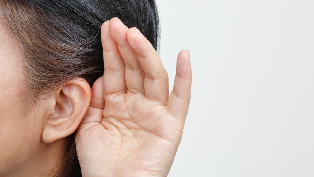 Close up on a person with a hand to their ear