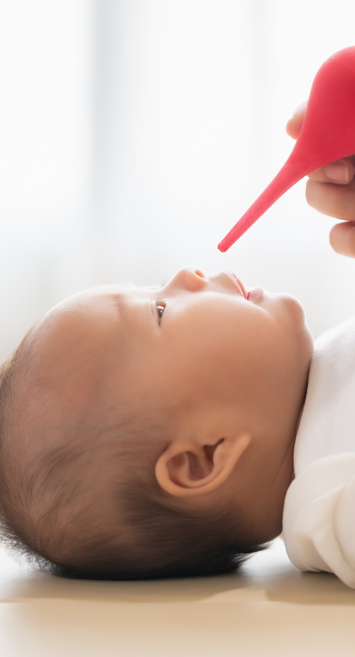 infant baby getting their nose cleared with bulb syringe by parent